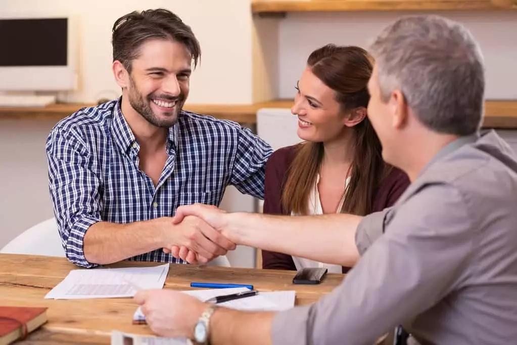 Handshake of a mature manager with a happy young couple at office